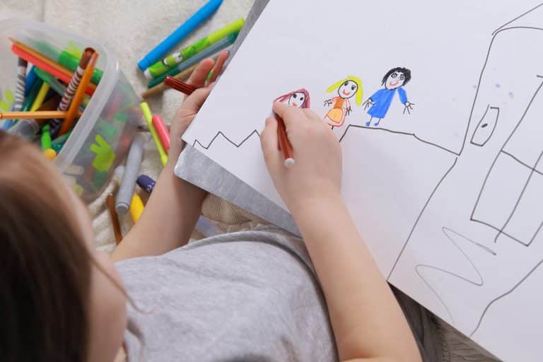 Un enfant dessine avec des feutres
