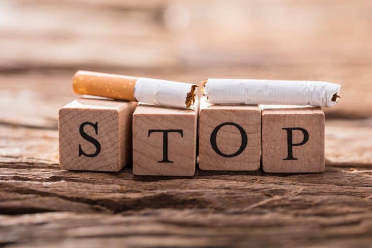Une cigarette déchirée sur des lettres de bois pour arrêter de fumer