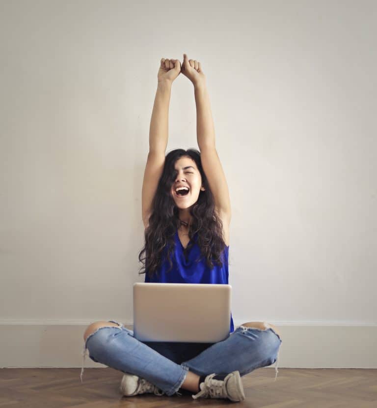 Une femme assise en tailleur lève les bras au ciel après avoir surmonter une dépression